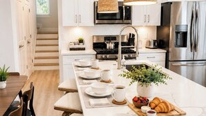 Uma cozinha moderna com armários brancos, eletrodomésticos de aço inoxidável e uma ilha central com assentos.