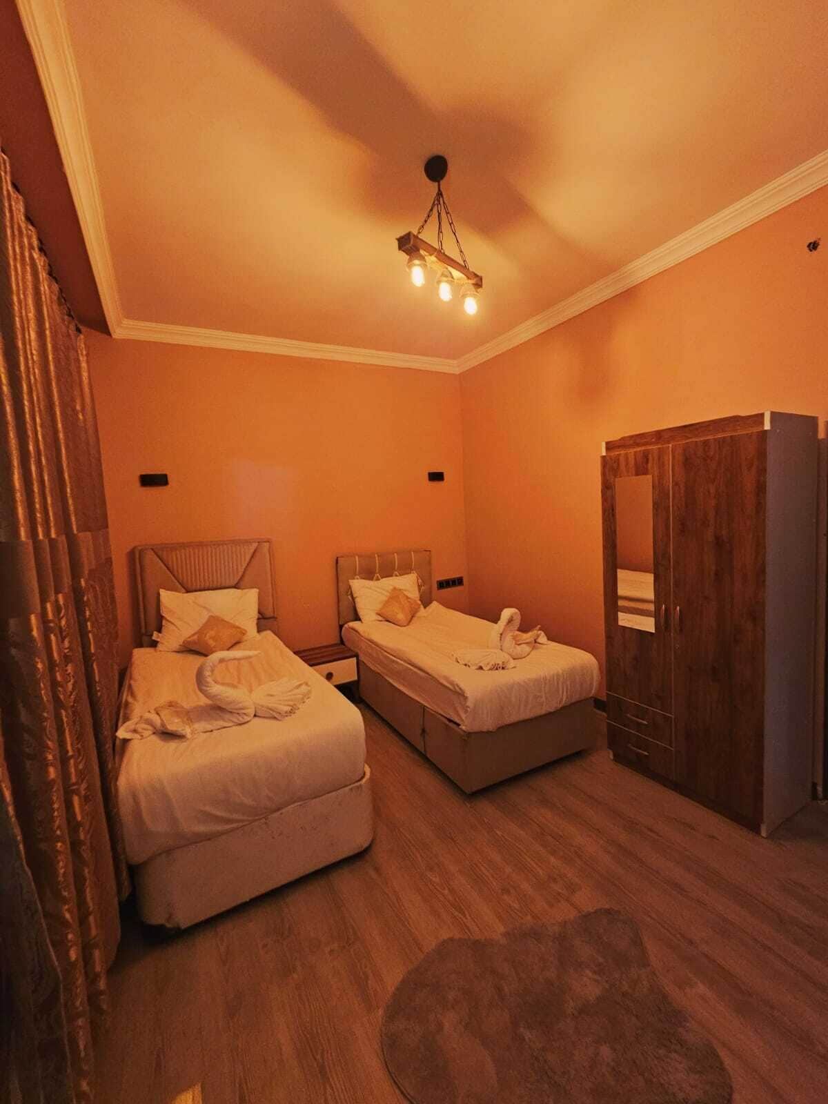 A hotel room with two beds, a wardrobe, and a ceiling light fixture.