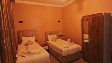 A hotel room with two beds, a wardrobe, and a ceiling light fixture.