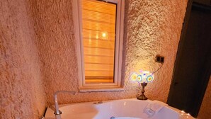 A hot tub with a glass of red wine and fruit on a tray. - NOVELA İN STONE HOUSE (Nevşehir)