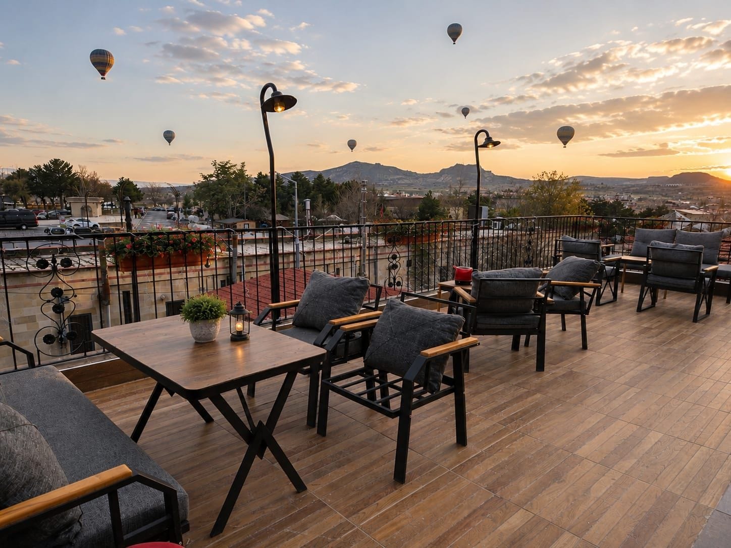 A rooftop terrace with outdoor seating, a view of the cityscape, and hot air balloons in the sky.