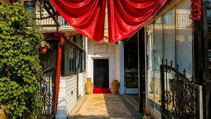 A narrow alleyway leading to a building with a red curtain and a large bow. - NOVELA İN STONE HOUSE (Nevşehir)