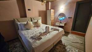 A bedroom with a bed, bedside table, lamp, mirror, and a door. - NOVELA İN STONE HOUSE (Nevşehir)
