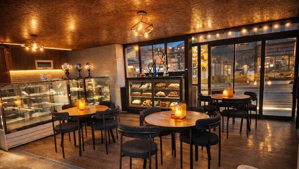 A cozy restaurant with round tables, chairs, and a display case of desserts. - NOVELA İN STONE HOUSE (Nevşehir)