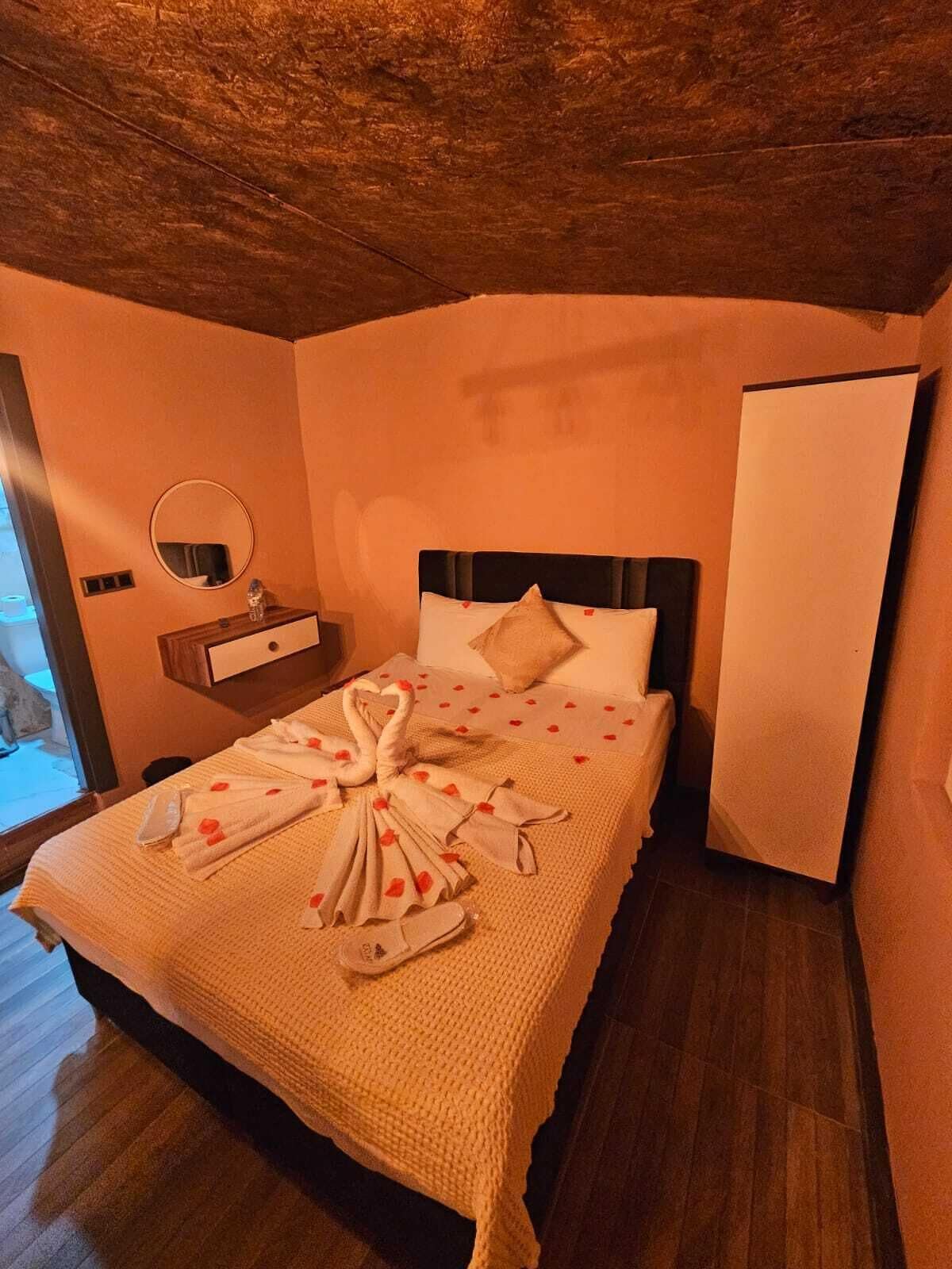 A hotel room with a bed, a bedside table, a mirror, and a wardrobe.