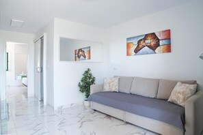 Uma sala de estar moderna com um sofá, uma planta em vaso e duas pinturas abstratas na parede.