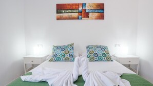 A hotel room with a bed, two nightstands, patterned pillows, a wall art piece, and a green rug. - Sunny Apartment in Costa de Antigua for 4 Guests (Nuevo Horizonte)