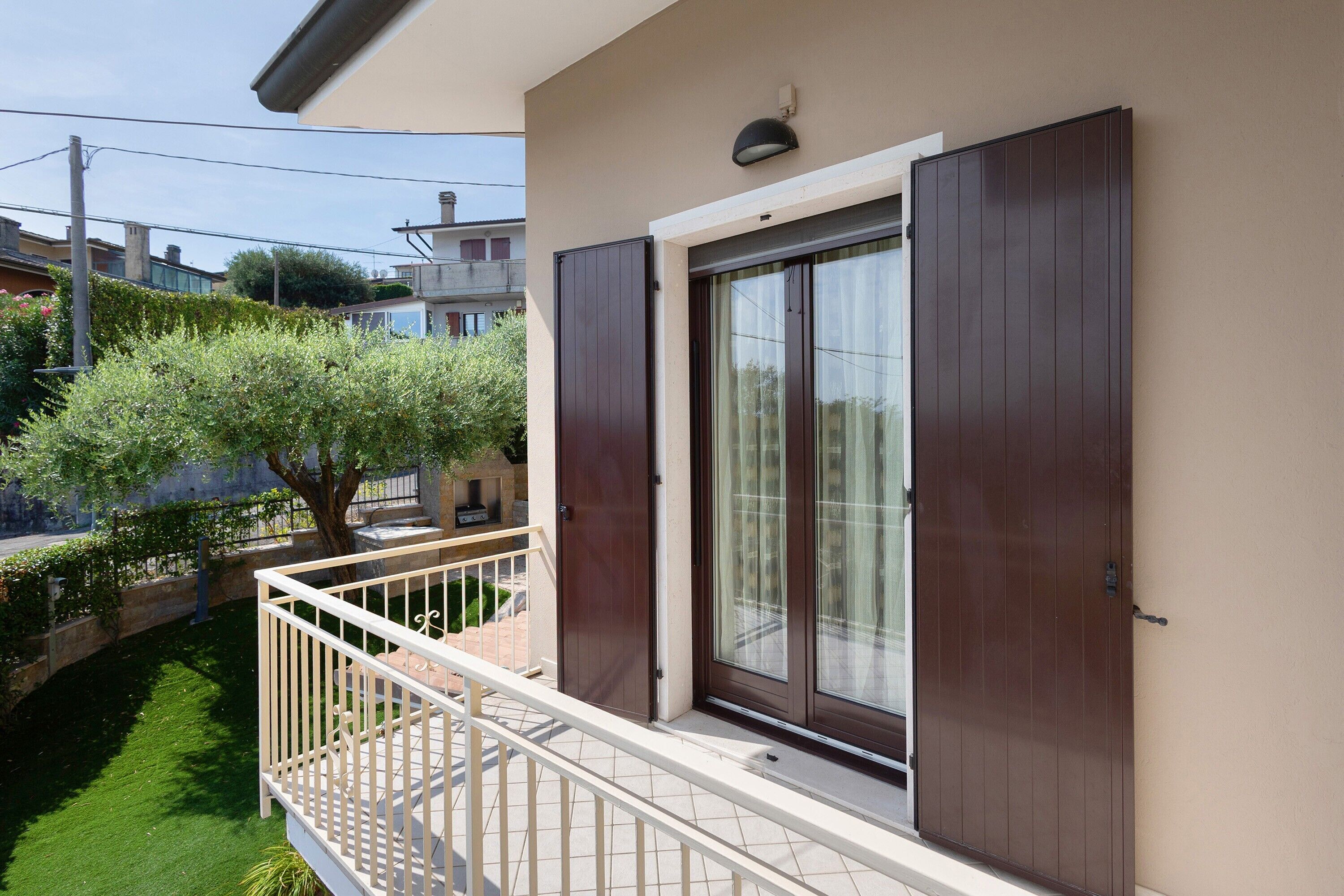 Un balcon avec une balustrade blanche, une porte marron et une fenêtre avec des rideaux.