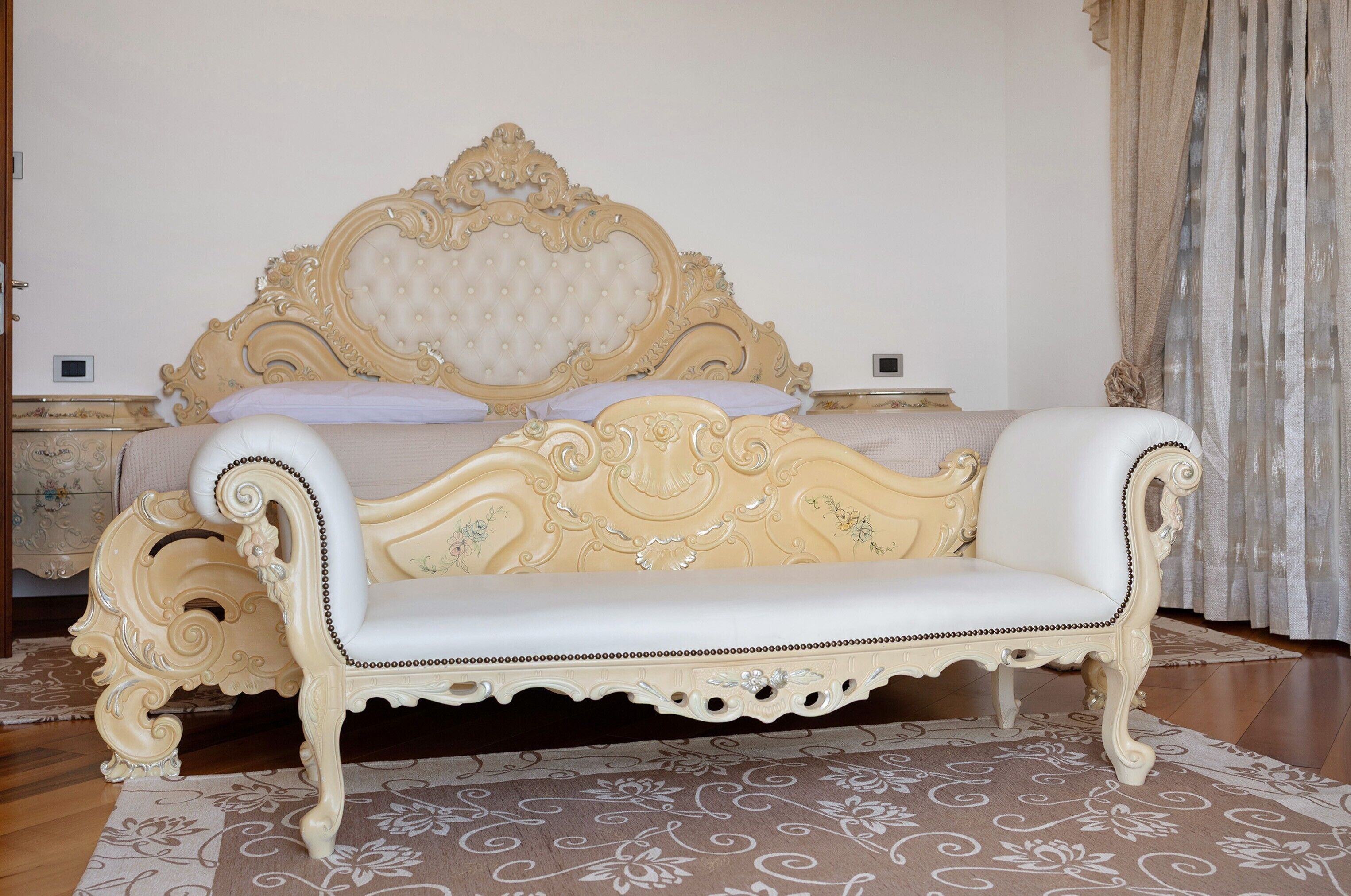 Un dormitorio con una cama grande, un sofá blanco y una alfombra estampada.