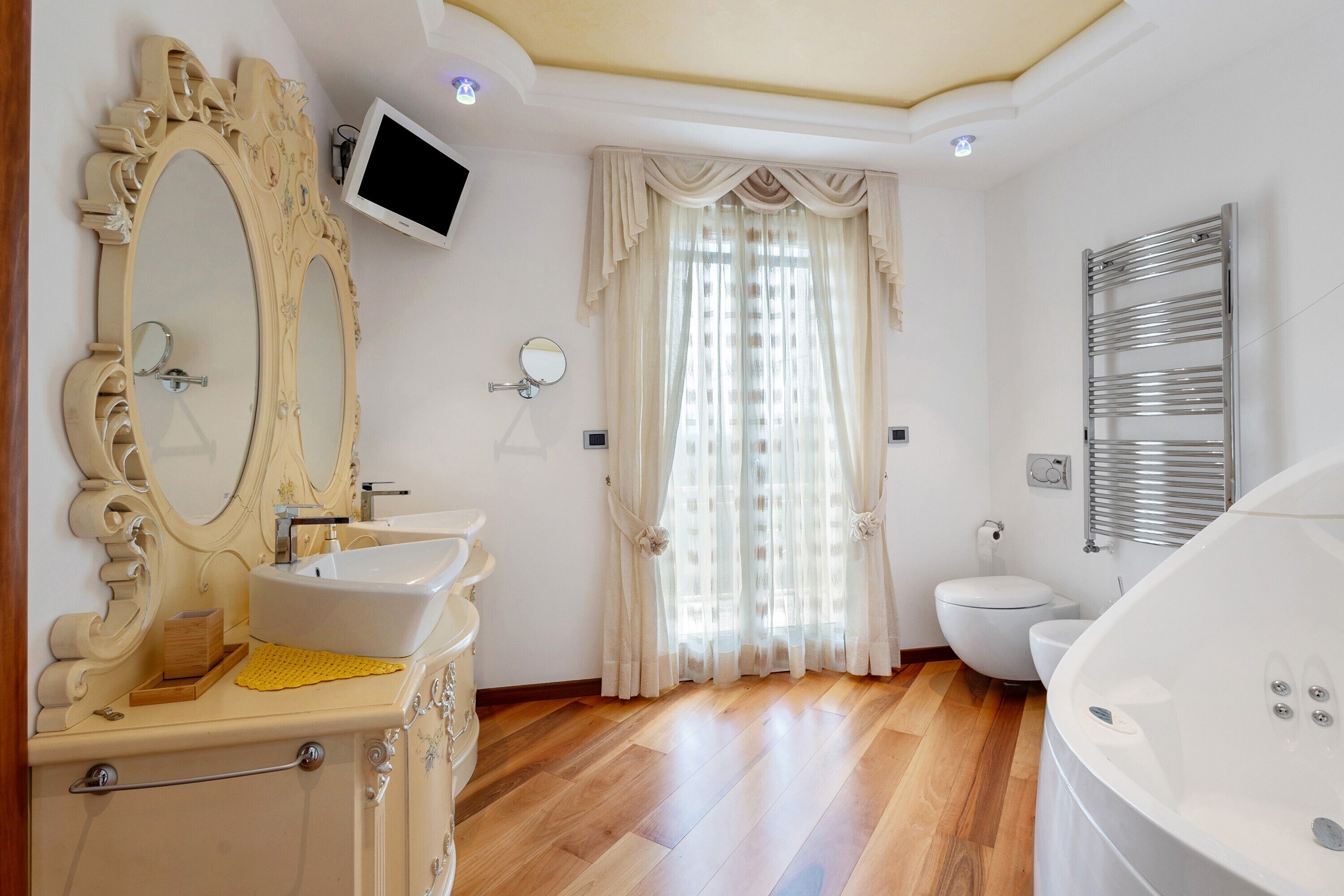 Une salle de bain comprenant un meuble-lavabo, un lavabo, un miroir, des toilettes et une baignoire.