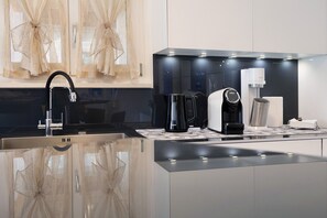 A modern kitchen with a stainless steel sink, a coffee maker, and a kettle.