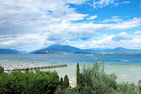 A coastal scene with a pier, clear water, and mountains in the background.