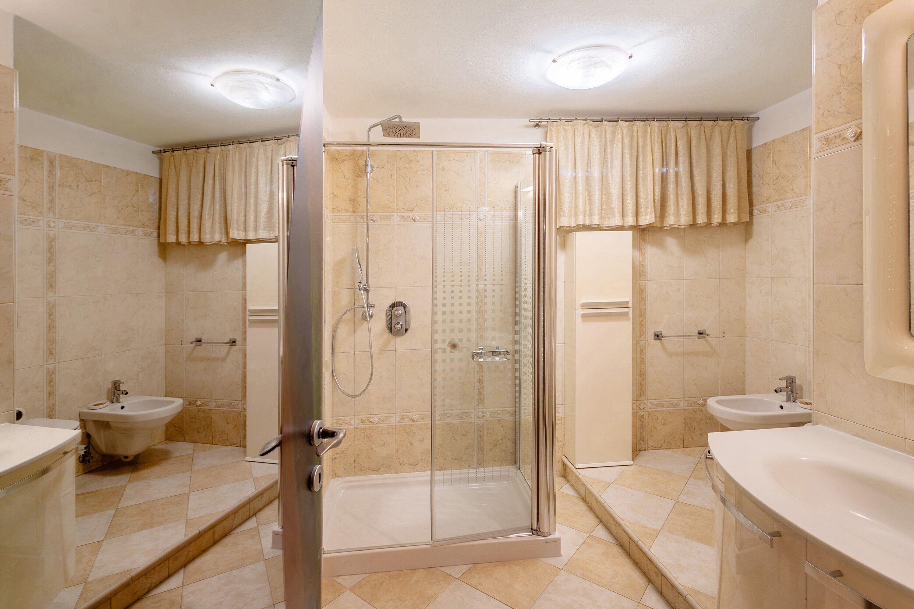 A bathroom with a glass-enclosed shower, two sinks, and a bathtub.