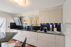 A modern kitchen with a black countertop, stainless steel appliances, and a dining area with a table and chairs.