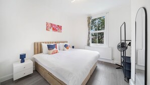 Una camera da letto con un letto, un comodino, una finestra e un ventilatore.