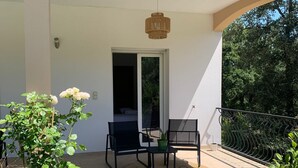 Zona d'estar a l'aire lliure coberta amb dues cadires, un taulell, una làmpada penjant i una planta en test.