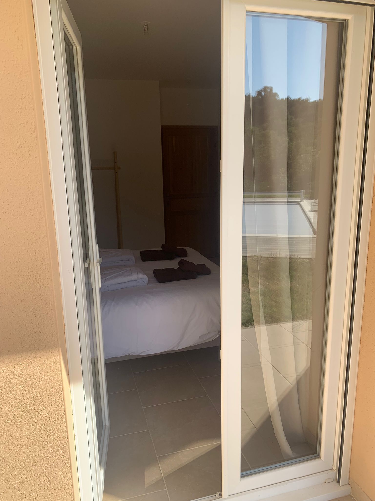 A room with a bed, a sliding glass door, and a view of a pool.