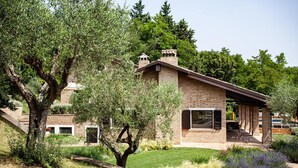 A modern brick house with a covered patio, surrounded by lush greenery and trees. - Room 'Resort Villa Paola - Camera Tordo' with Sea View, Wi-Fi and Air Conditioning (Longiano)