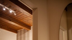 A bedroom with a wooden ceiling, a bed with a headboard, a bedside table, and a mirror. - Room 'Resort Villa Paola - Camera Tordo' with Sea View, Wi-Fi and Air Conditioning (Longiano)