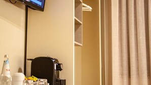 A hotel room with a flat-screen TV mounted on the wall, a desk with a coffee maker, and a built-in shelving unit. - Room 'Resort Villa Paola - Camera Tordo' with Sea View, Wi-Fi and Air Conditioning (Longiano)