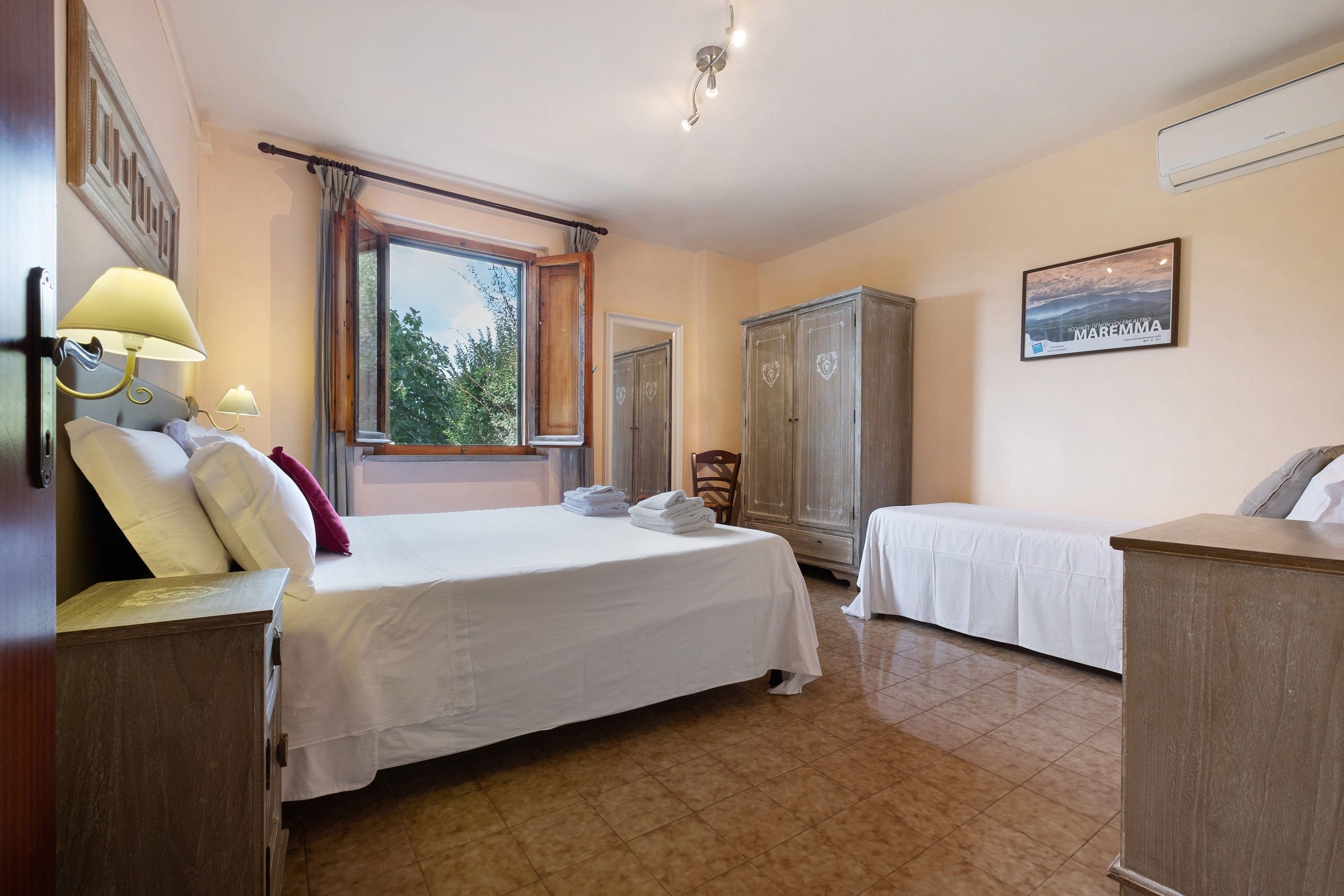 A hotel room with a bed, a desk, a wardrobe, and a window with curtains.