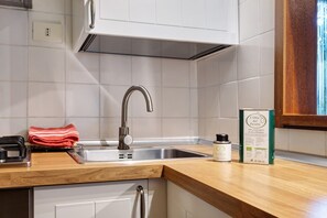 Cuina amb un rentaplat de formó inoxidable, taulell de fusta i tovallola vermella.