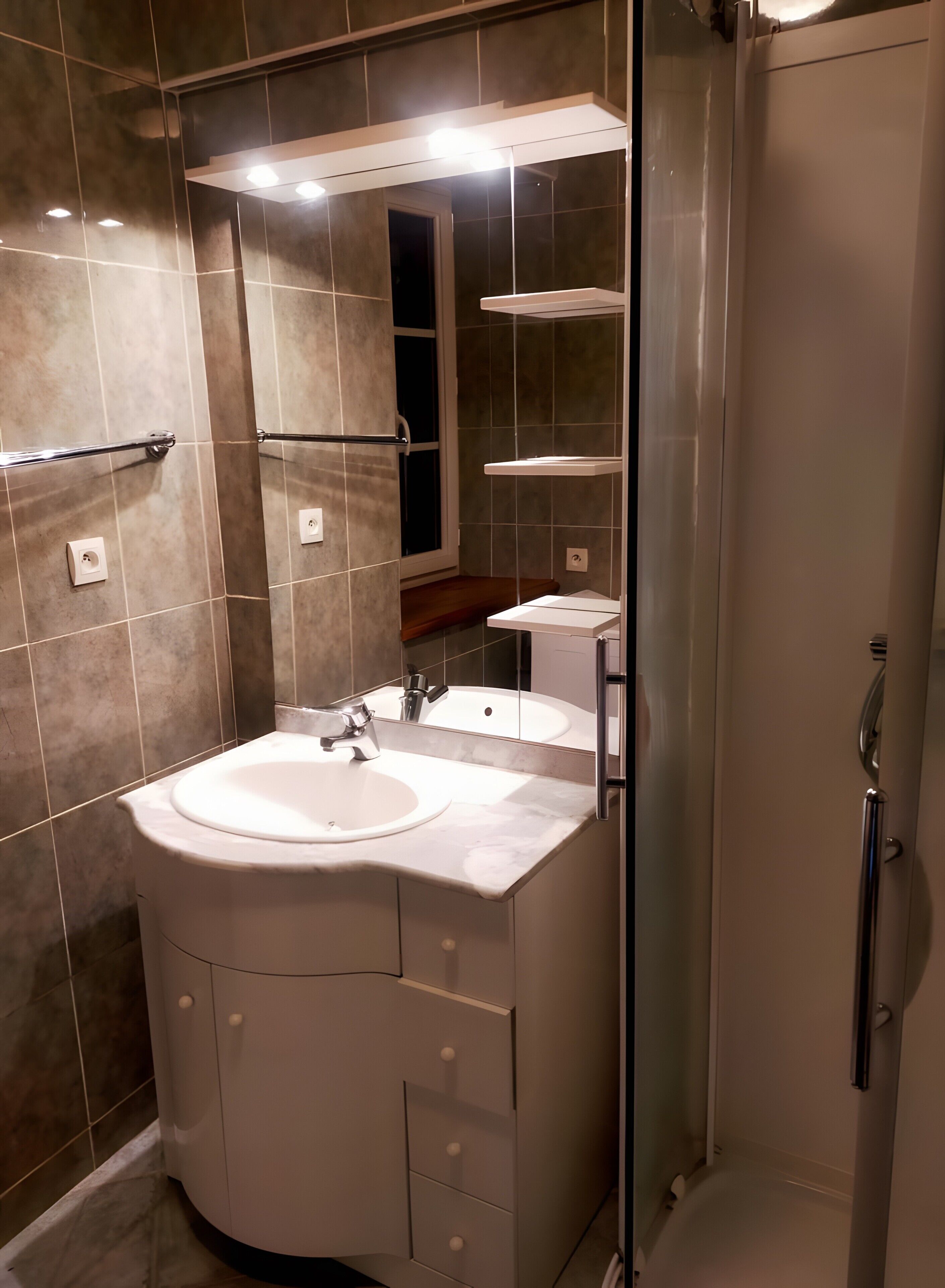 A modern bathroom with a sink, mirror, and shower.