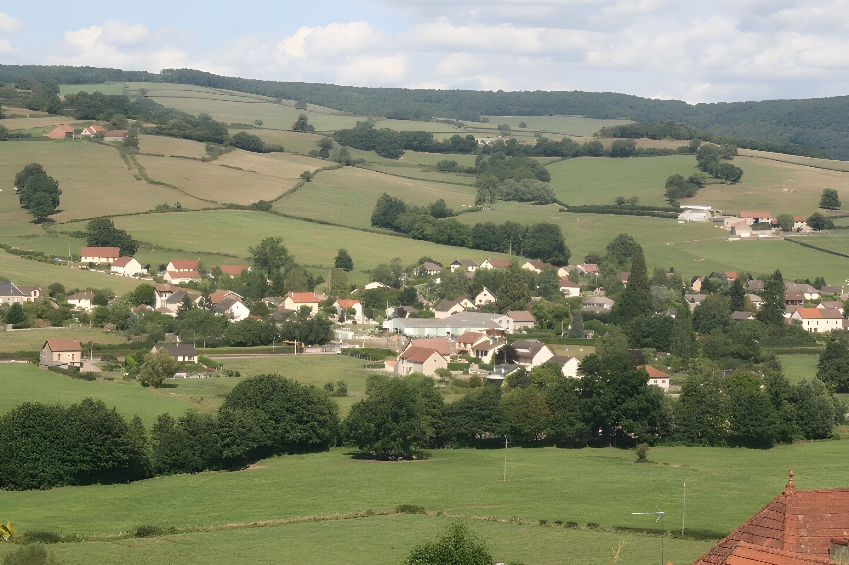 A rural village with houses spread across rolling green fields.