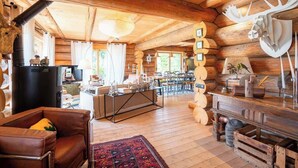Ein Holzblockhaus-Interieur mit Kamin, Holzmöbeln und einem Essbereich.