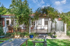 Il s’agit d’une propriété résidentielle dotée d’une terrasse, d’une table en bois, d’une chaise, d’une plante en pot et d’un petit jardin.
