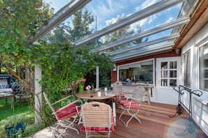 Une terrasse extérieure avec une plateforme en bois, une table ronde et des chaises en métal.