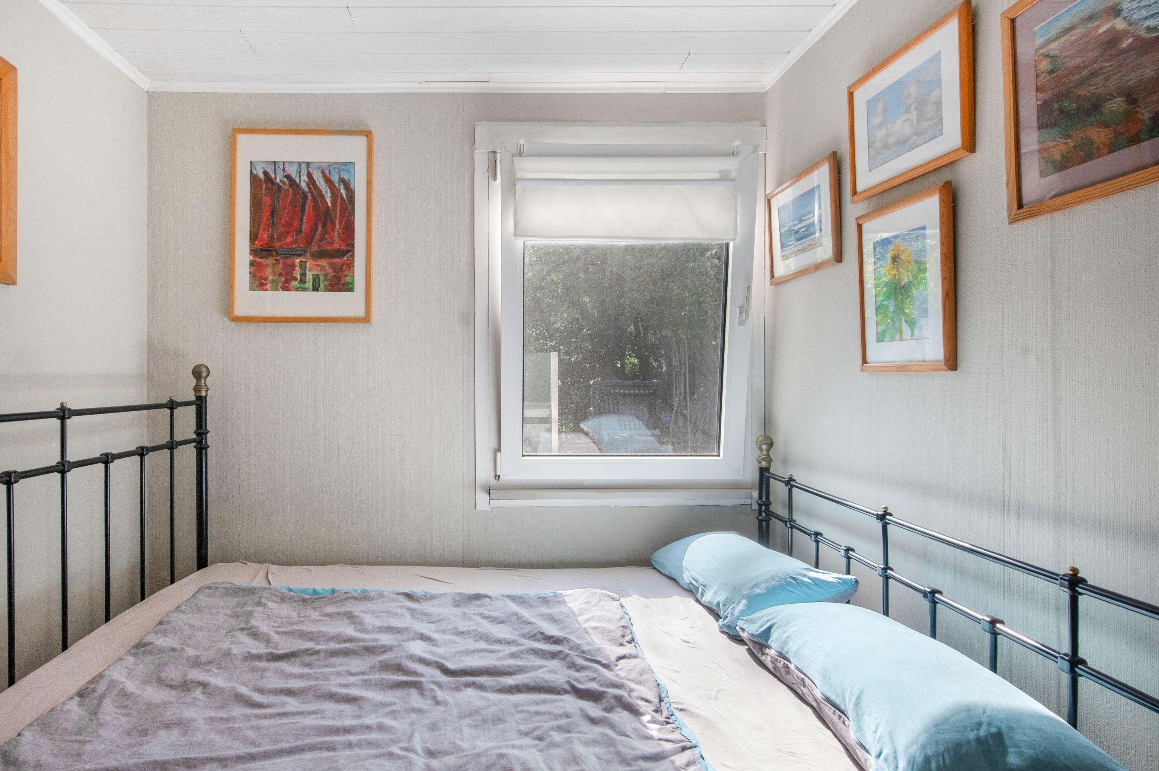 Um quarto com cama, janela com vista e várias quadros nas paredes.