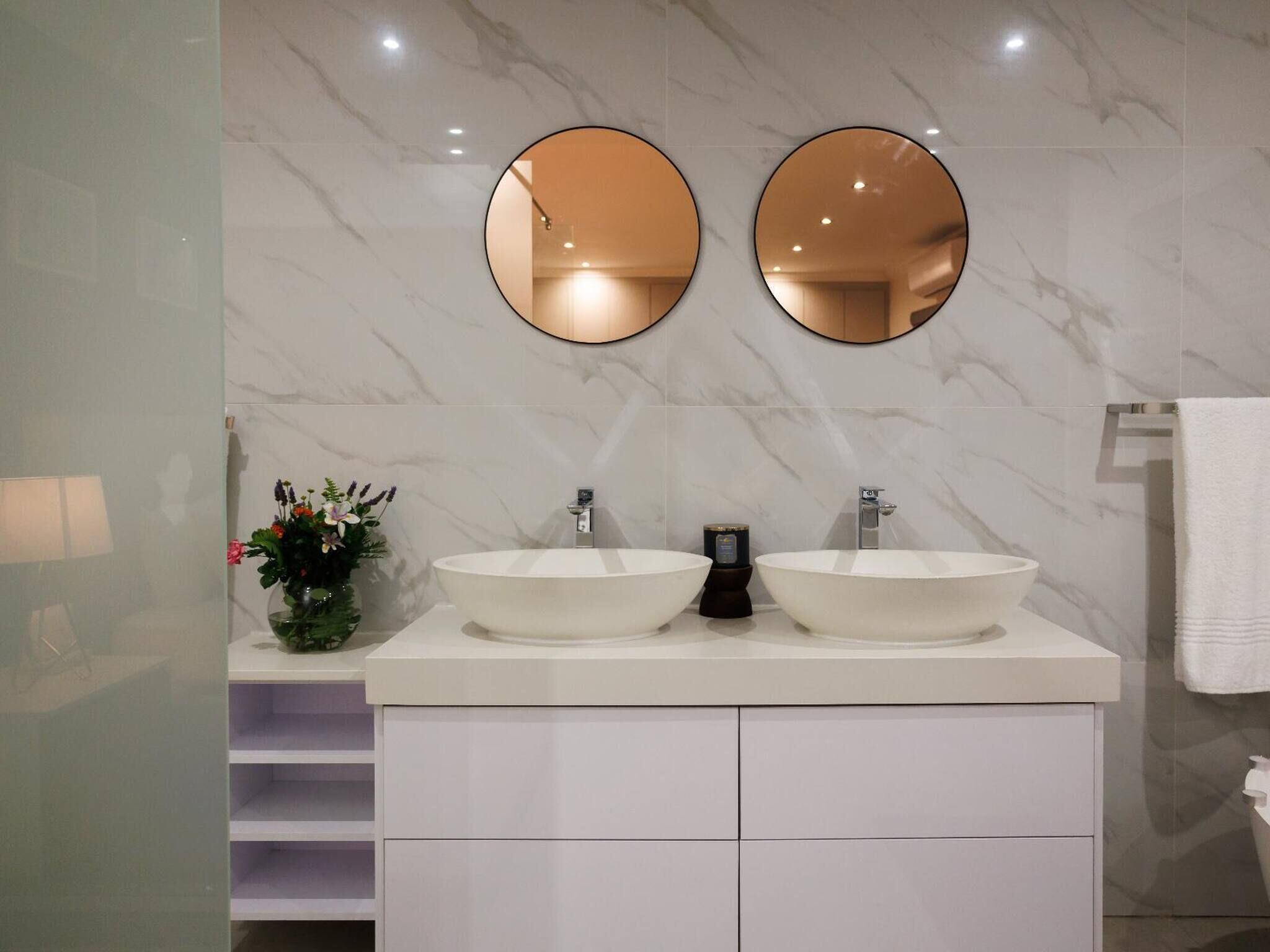A bathroom with two large white sinks, a mirror, and a small plant on the vanity.