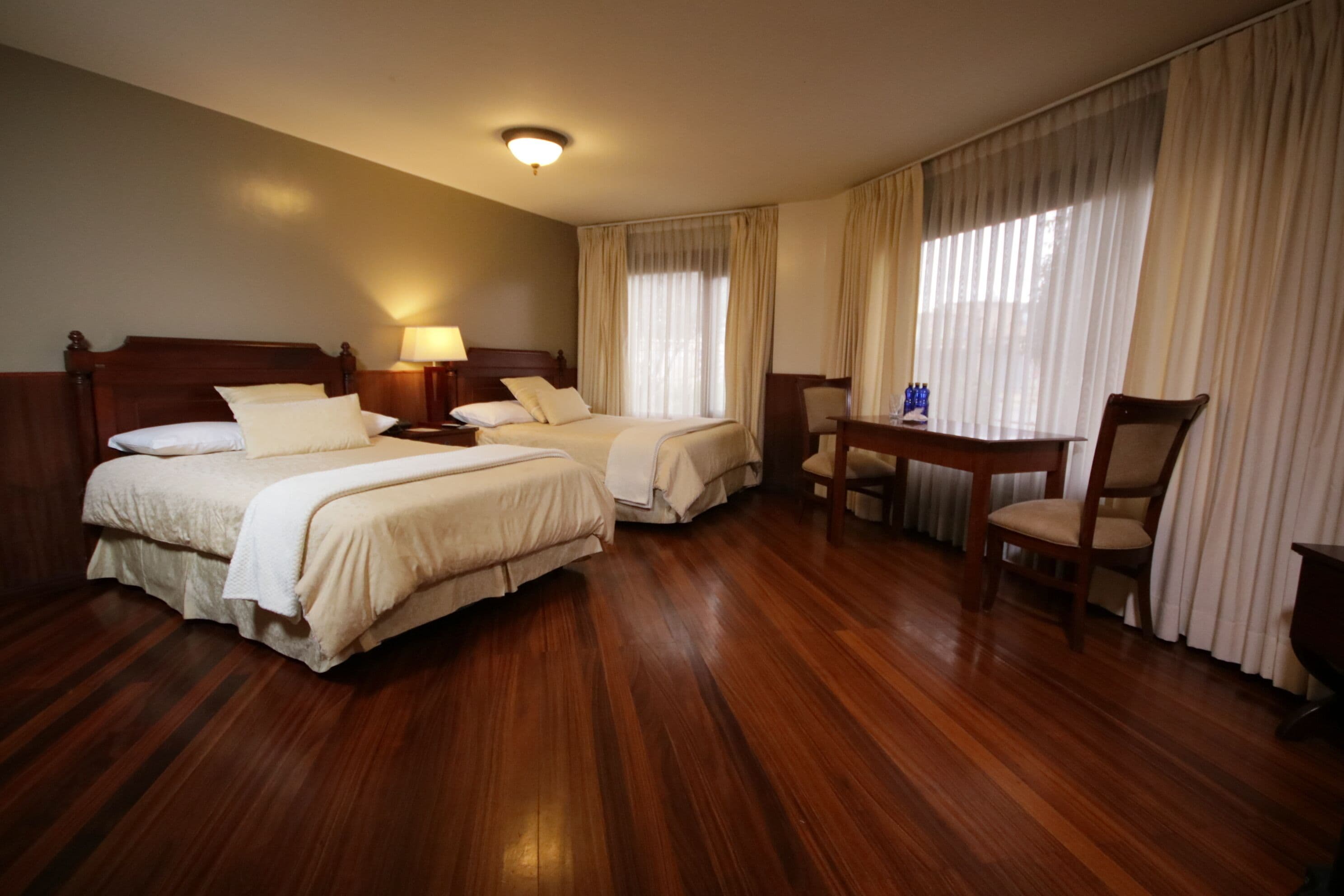 A hotel room with two beds, a desk, and a chair.