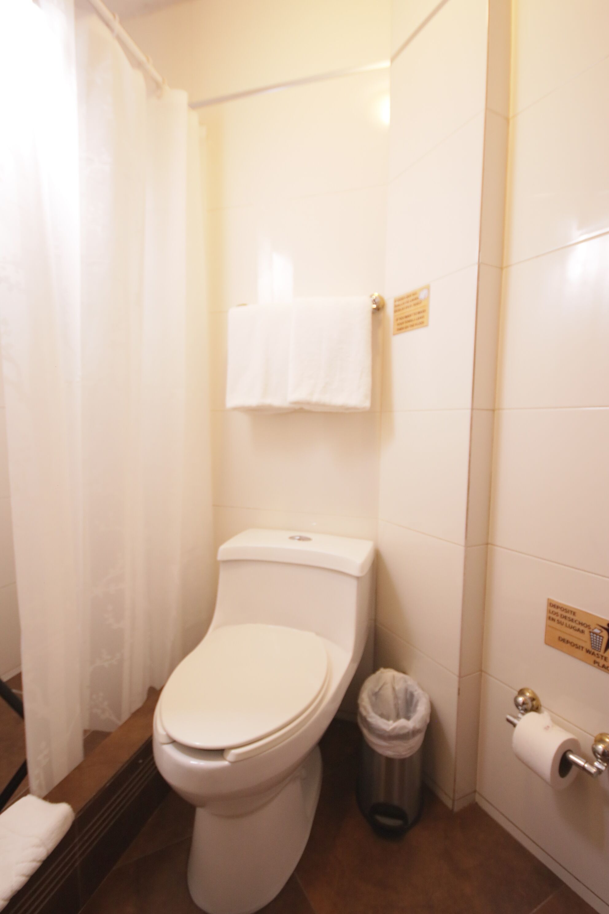 Un baño con inodoro, un bote de basura y un perchero para toallas.