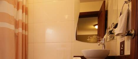 A bathroom with a toilet, sink, mirror, and striped shower curtain.