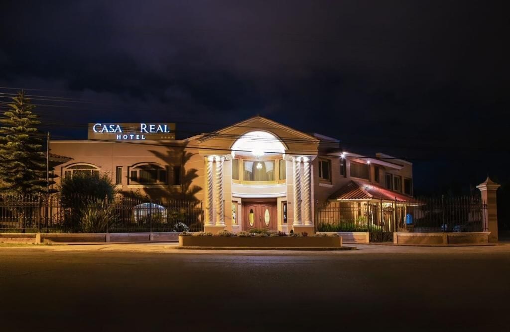 A hotel with a prominent entrance, a sign reading 'CASA REAL HOTEL,' and a well-lit facade.