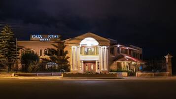 A hotel with a prominent entrance, a sign reading 'CASA REAL HOTEL,' and a well-lit facade.