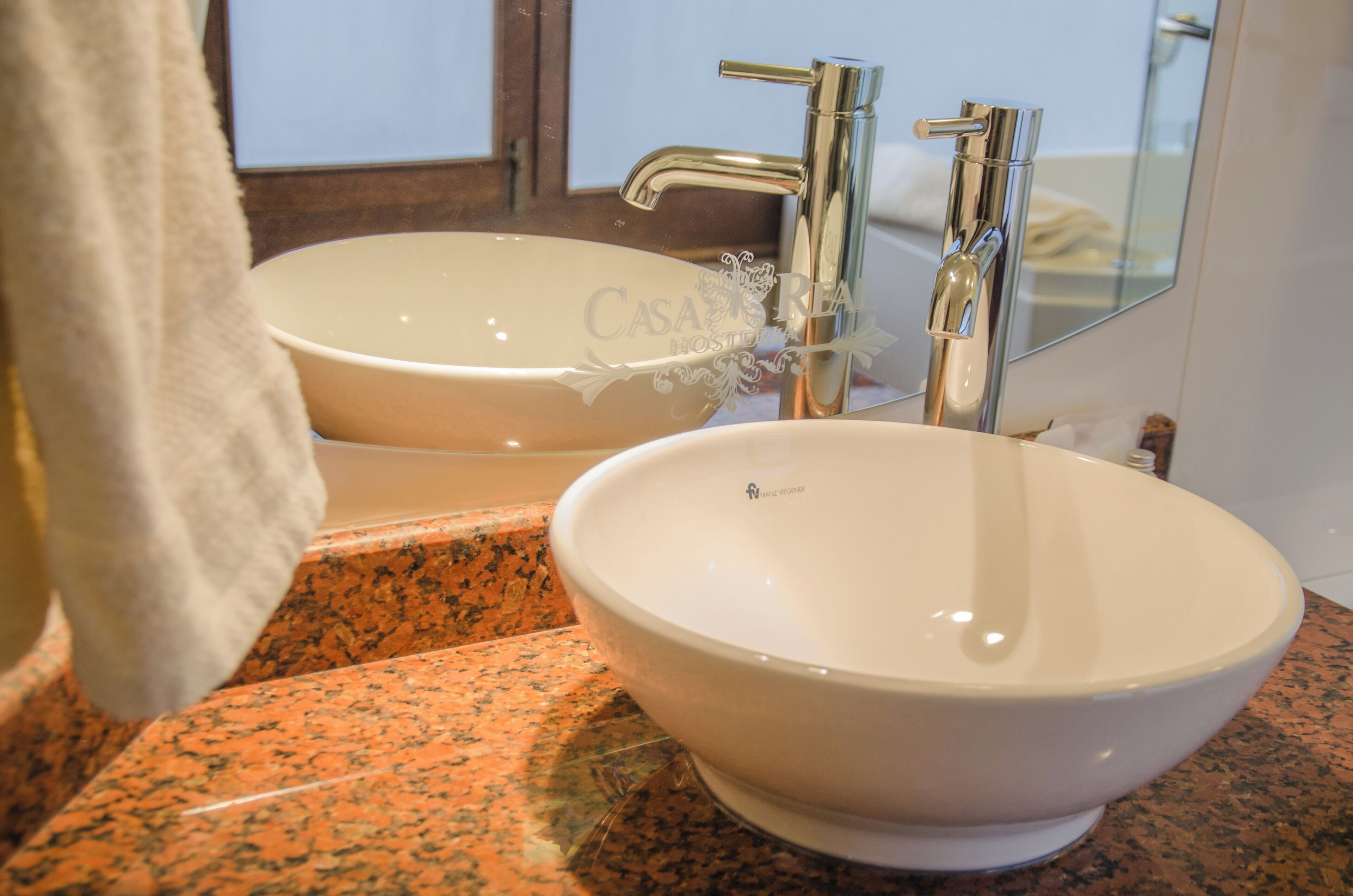 A bathroom with two sinks, a mirror, and a towel hanging on the wall.