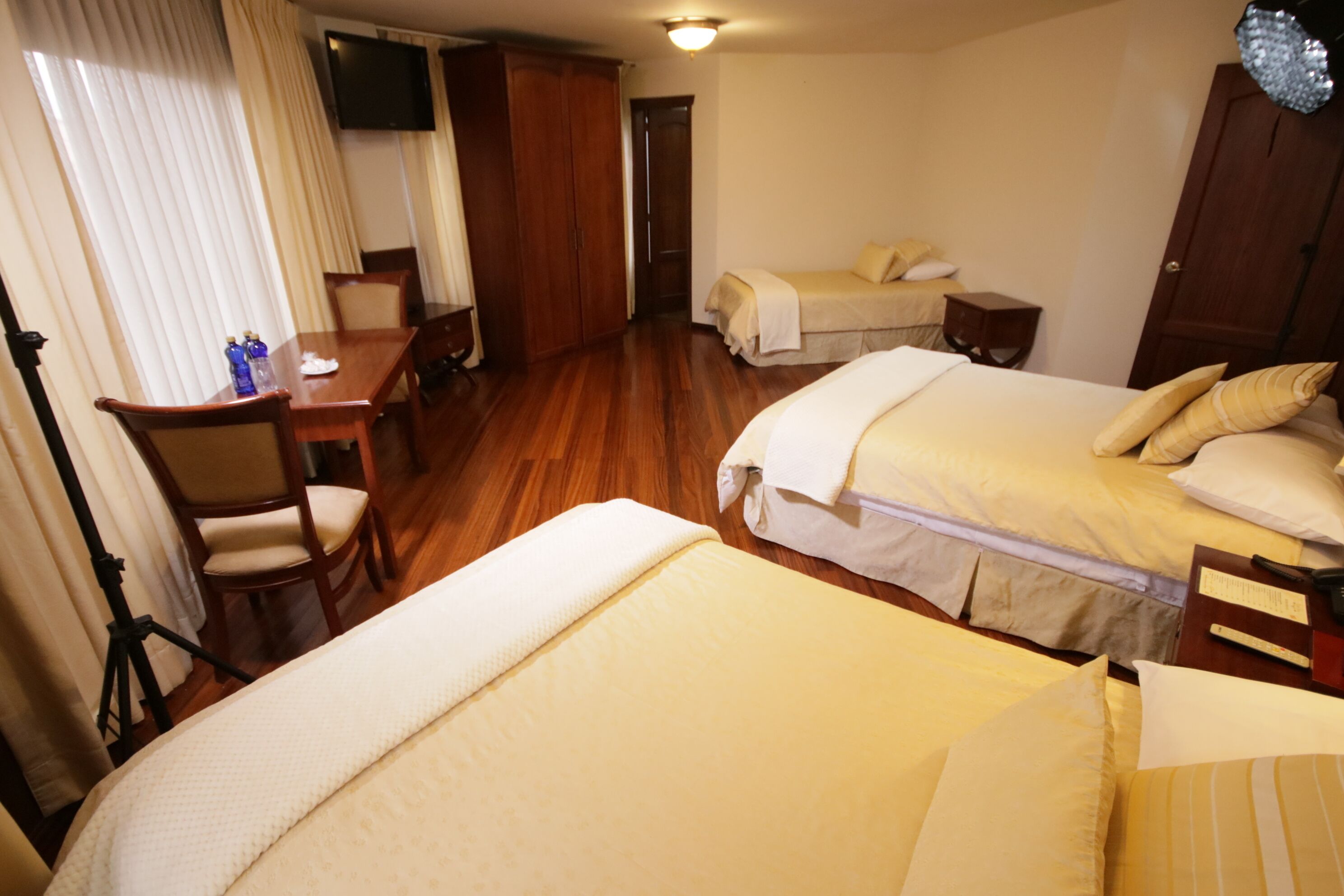 Ein Hotelzimmer mit zwei Betten, einem Schreibtisch und einem Fernseher.