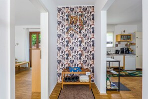 Un pasillo con papel tapiz de temática canina, un banco de madera con toallas y una zona de cocina con armarios y una cafetera.