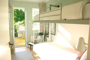 Ein Schlafraum mit Etagenbett und Blick auf einen Balkon sowie Gartenmöbel.