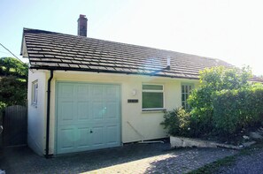 Ein eingeschossiges Haus mit einer Garagentür, einem Schornstein und einem kleinen Fenster.