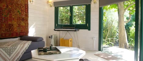 A room with a bed, a coffee table, a window, and a view of greenery outside.