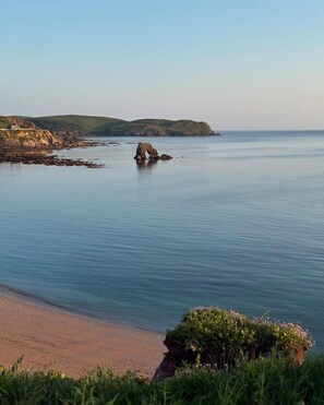 A coastal landscape with a clear sky, calm sea, and a rocky outcrop in the distance. - Abbotscot near Bantham, S. Devon (West Buckland, Bantham)