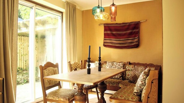 A dining area with a wooden table, chairs, and a bench with floral upholstery. - Abbotscot near Bantham, S. Devon (West Buckland, Bantham)