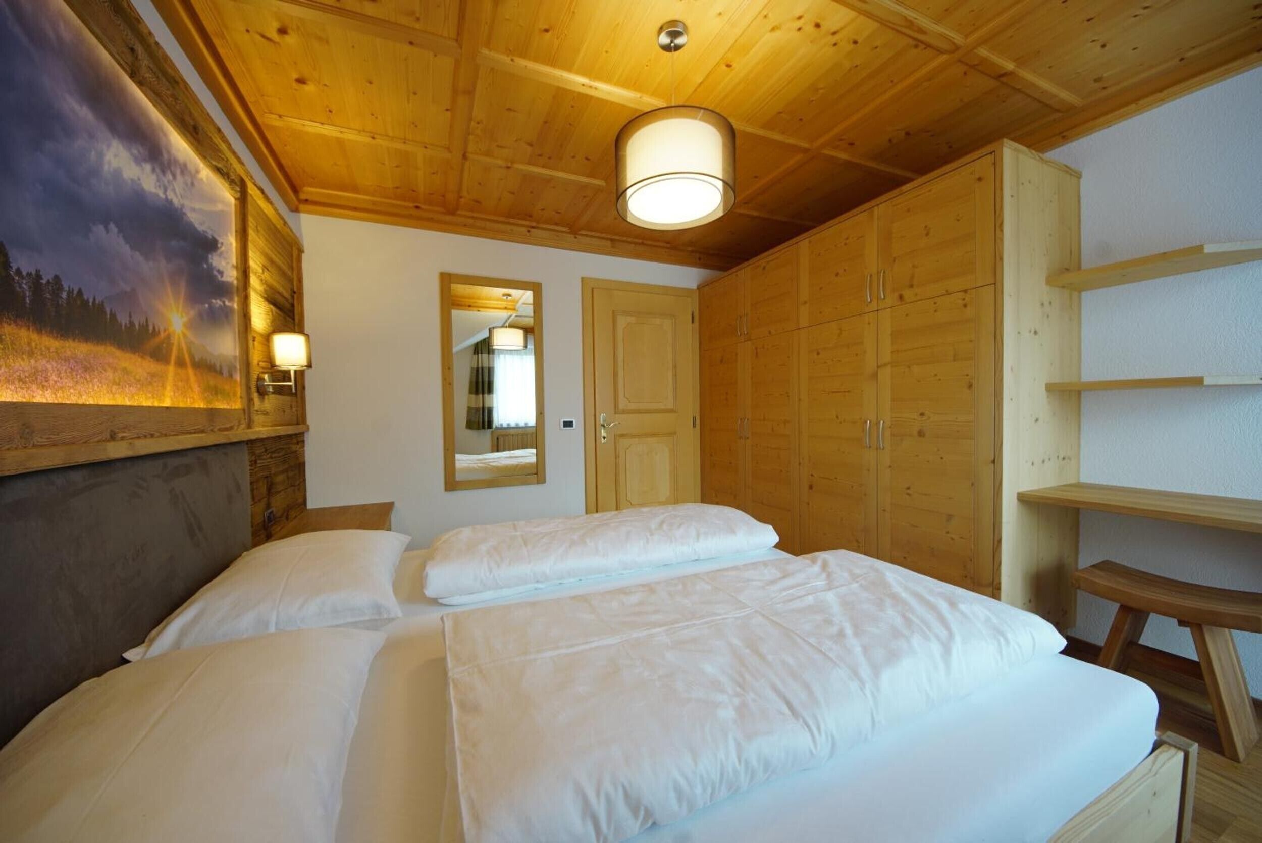 Une pièce aux murs lambrissés, avec un lit, un miroir et un tableau accroché au mur.
