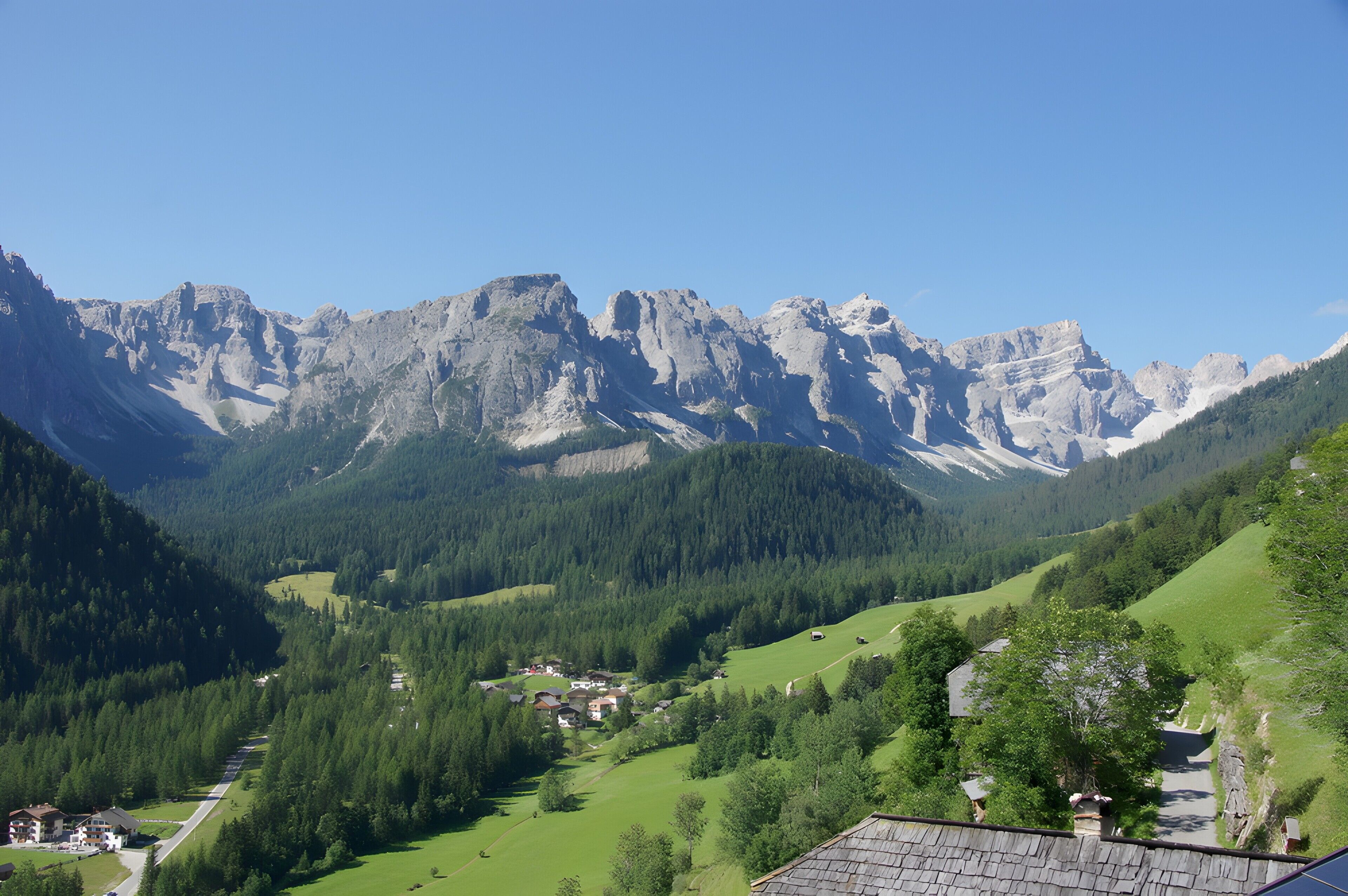 Un paisaje montañoso con un valle, un pequeño asentamiento y cielo despejado.