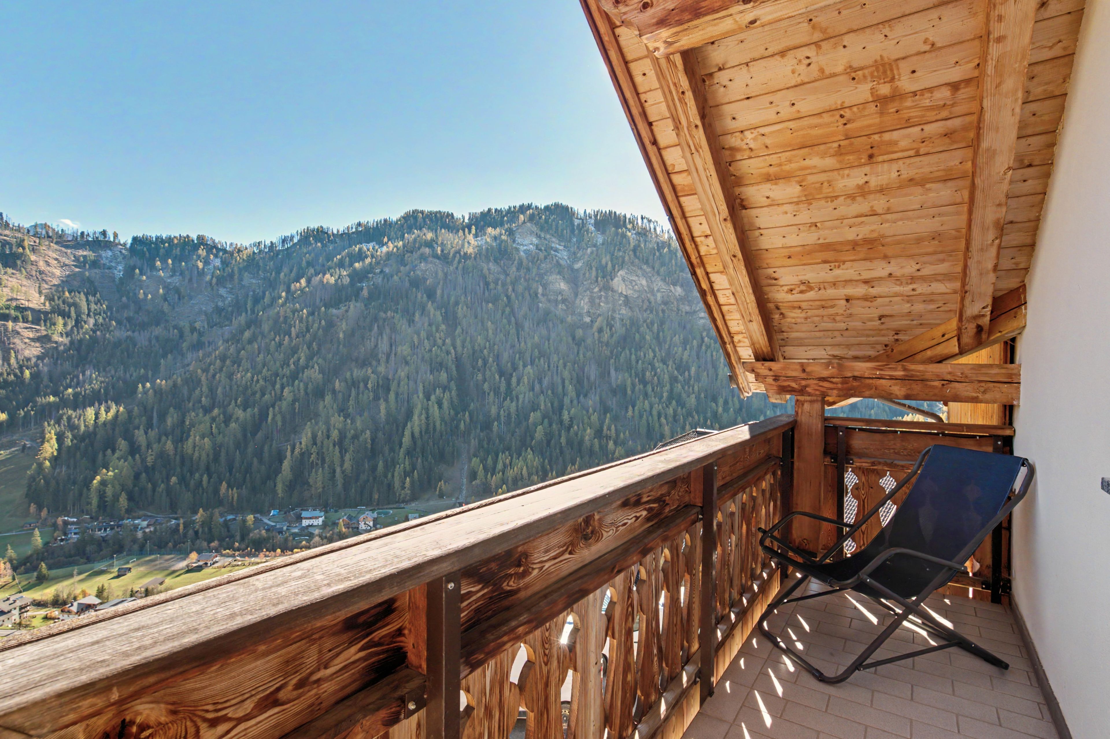 Un balcone in legno con vista su una montagna boscosa.