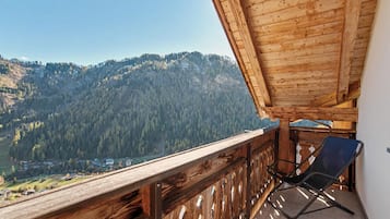 Un balcone in legno con vista su una montagna boscosa.